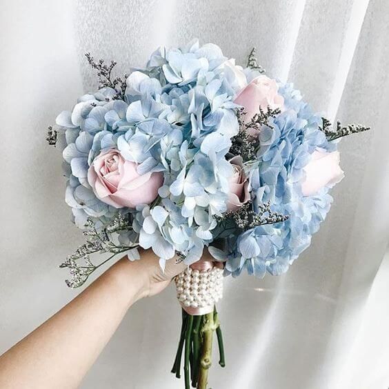 a person holding a bouquet of blue and pink flowers