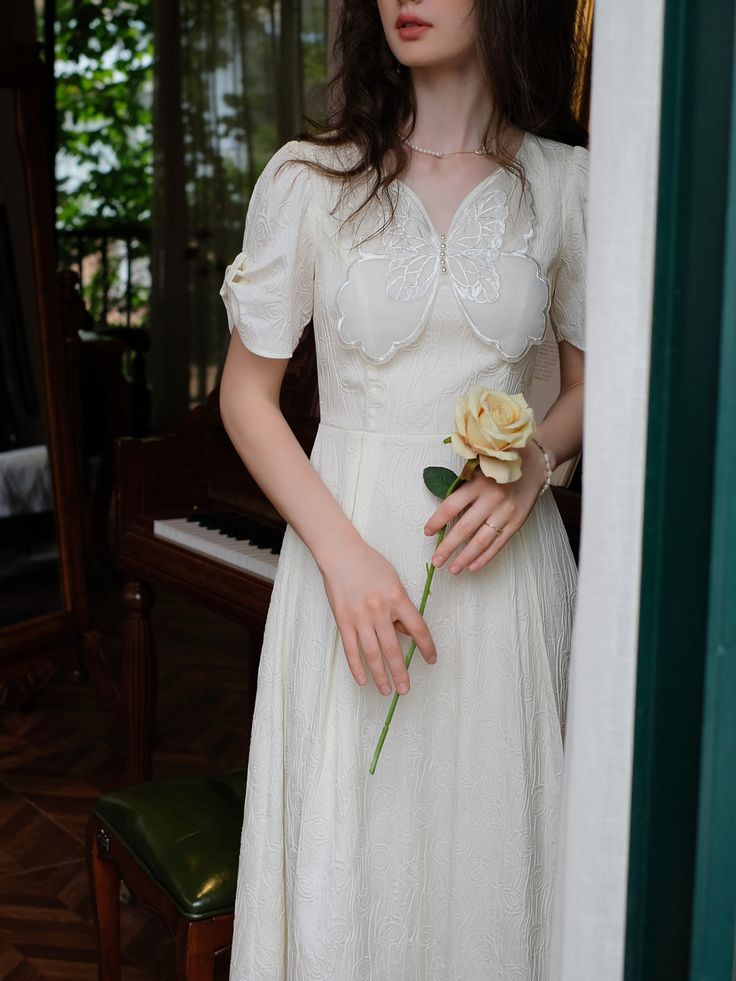 a woman in a white dress holding a flower