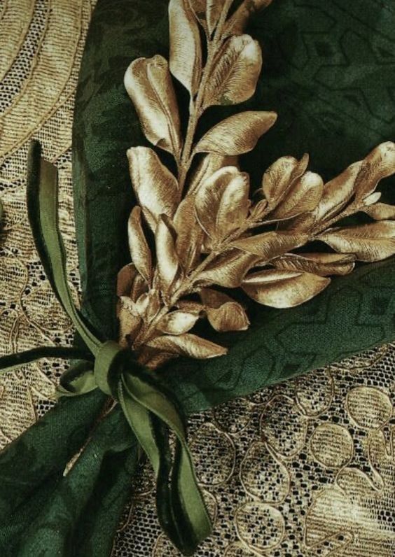 a green and gold cloth with some leaves on top of it next to a lace doily