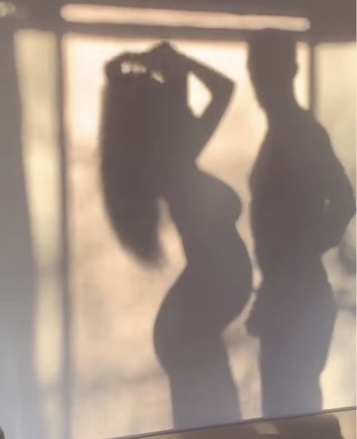 the shadow of a man and woman standing next to each other in front of a window