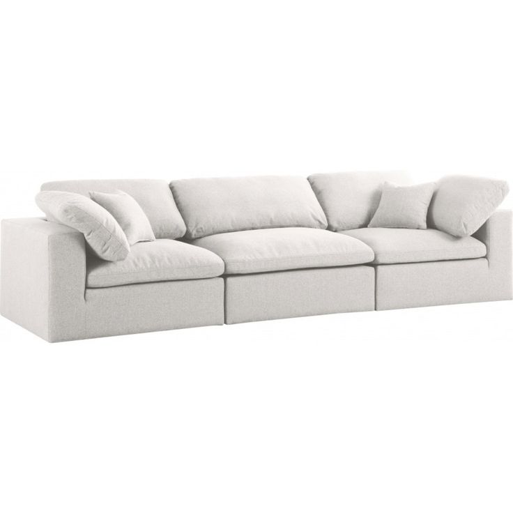 a white couch with four pillows on it's back and one arm facing the camera