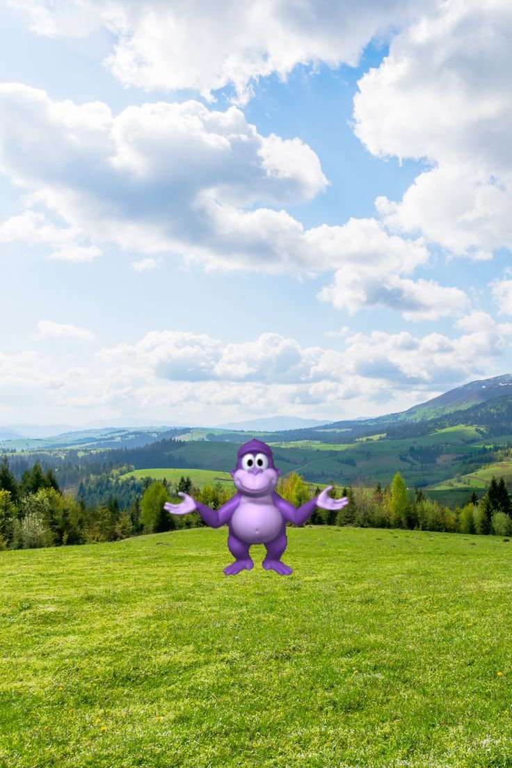 an inflatable purple monster standing on top of a lush green field