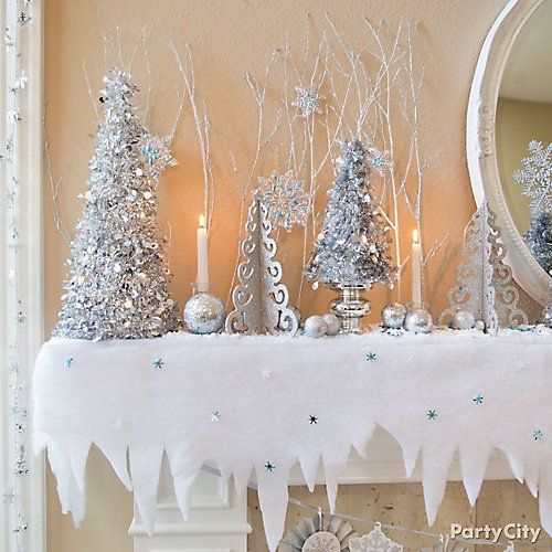 a mantel decorated with silver and white christmas trees, snowflakes and candles