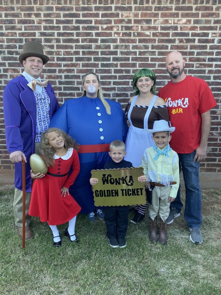 a group of people standing next to each other in front of a brick wall holding a sign