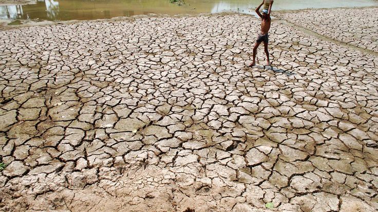 a man standing on top of a dry grass field next to a body of water