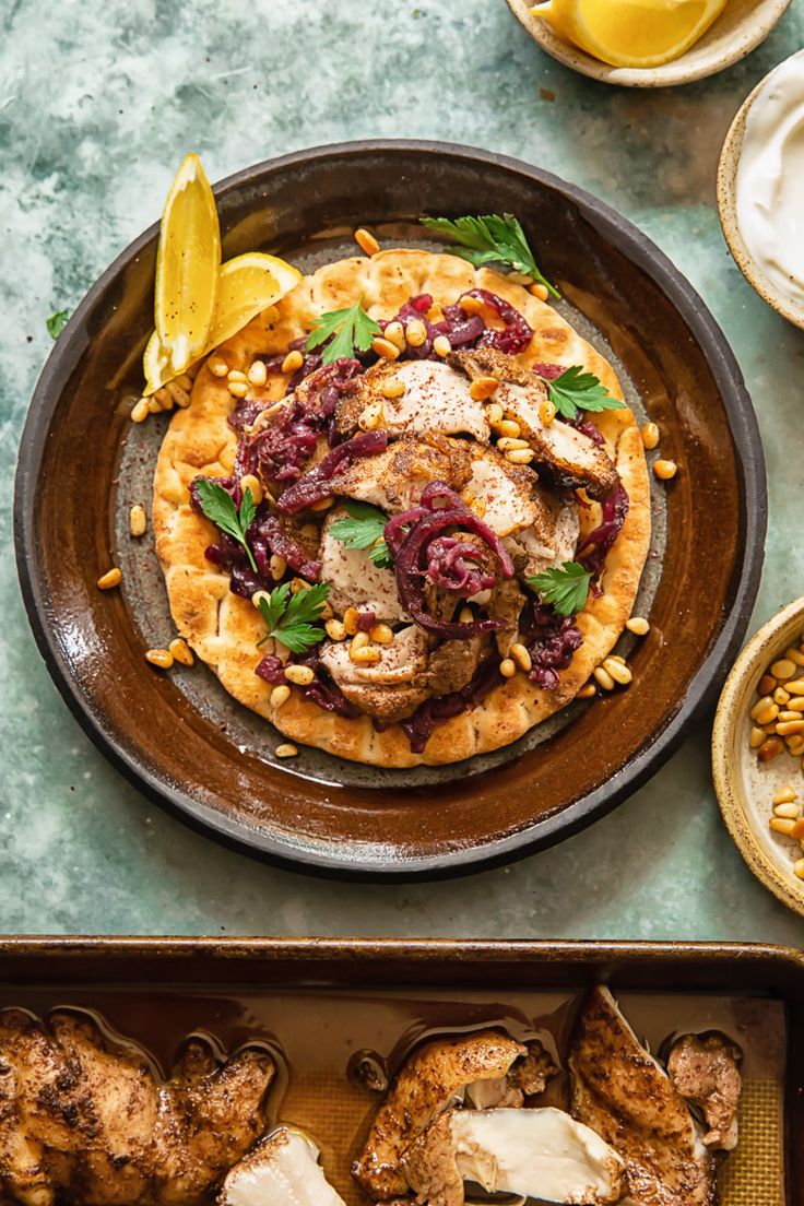 an overhead view of some food on a plate with lemon wedges and other dishes