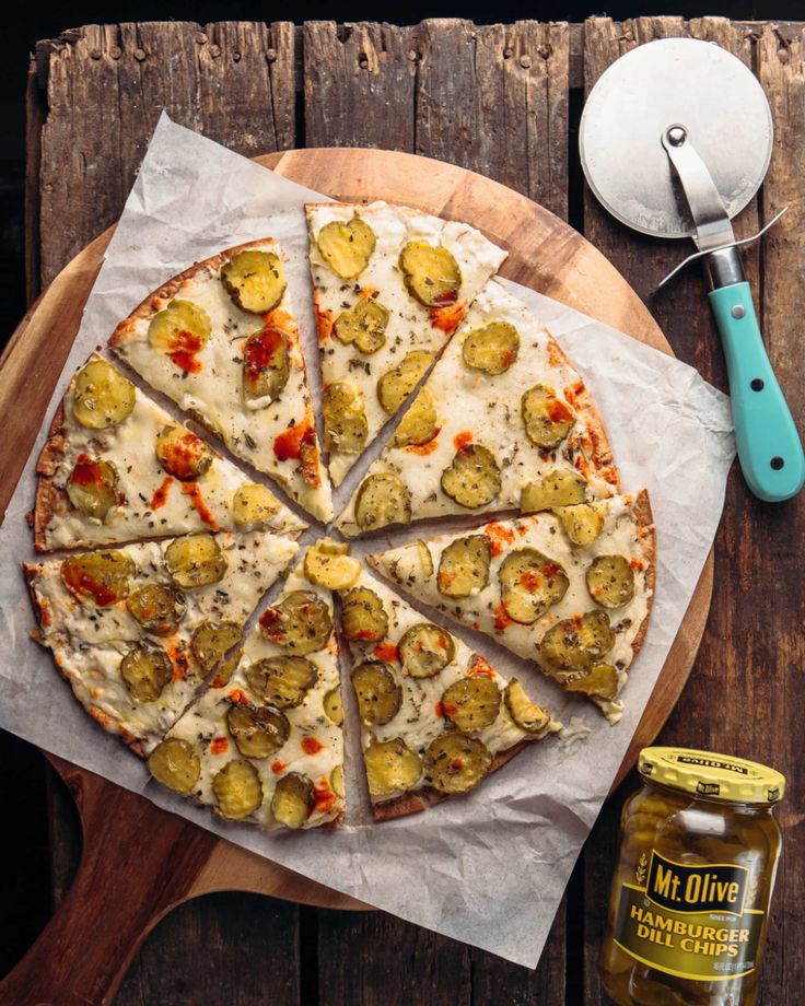 a pizza sitting on top of a wooden cutting board next to a jar of mustard