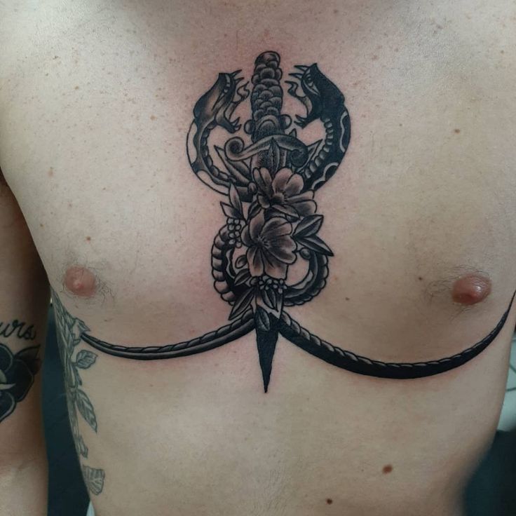 a man with a tattoo on his chest has a knife and flowers in the center