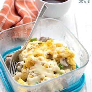 a plastic container filled with food next to a cup of coffee