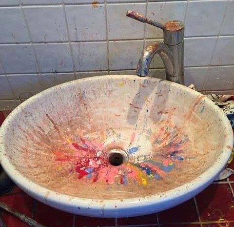 a dirty sink with colorful paint all over the bowl and faucet in it