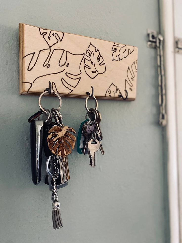 several keys hang on the wall with a wooden key holder attached to it's side