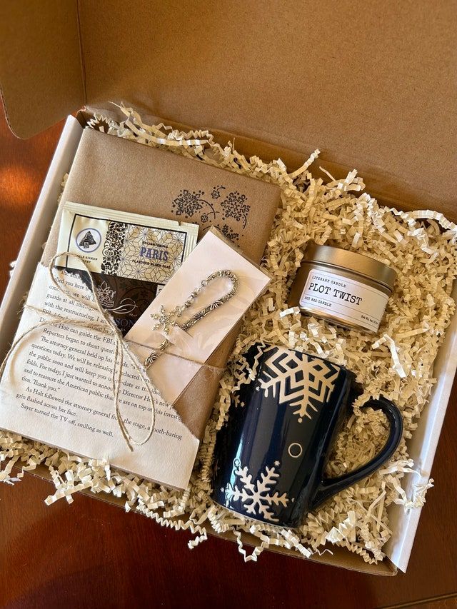 an open box containing a coffee cup, mug and some kind of paper with snowflakes on it