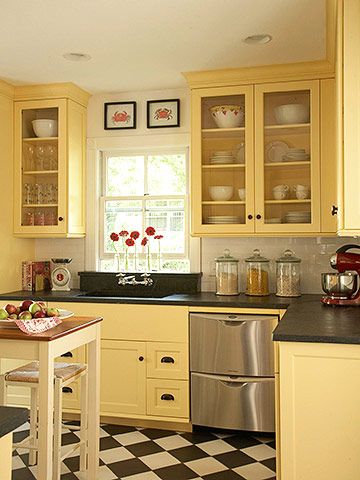 a kitchen with yellow cabinets and checkered flooring on the tile counter tops, along with a stainless steel dishwasher