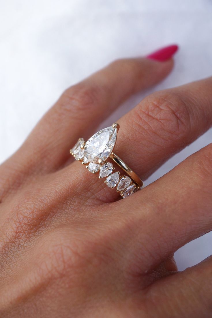 a woman's hand with a gold ring and three stones on the middle finger