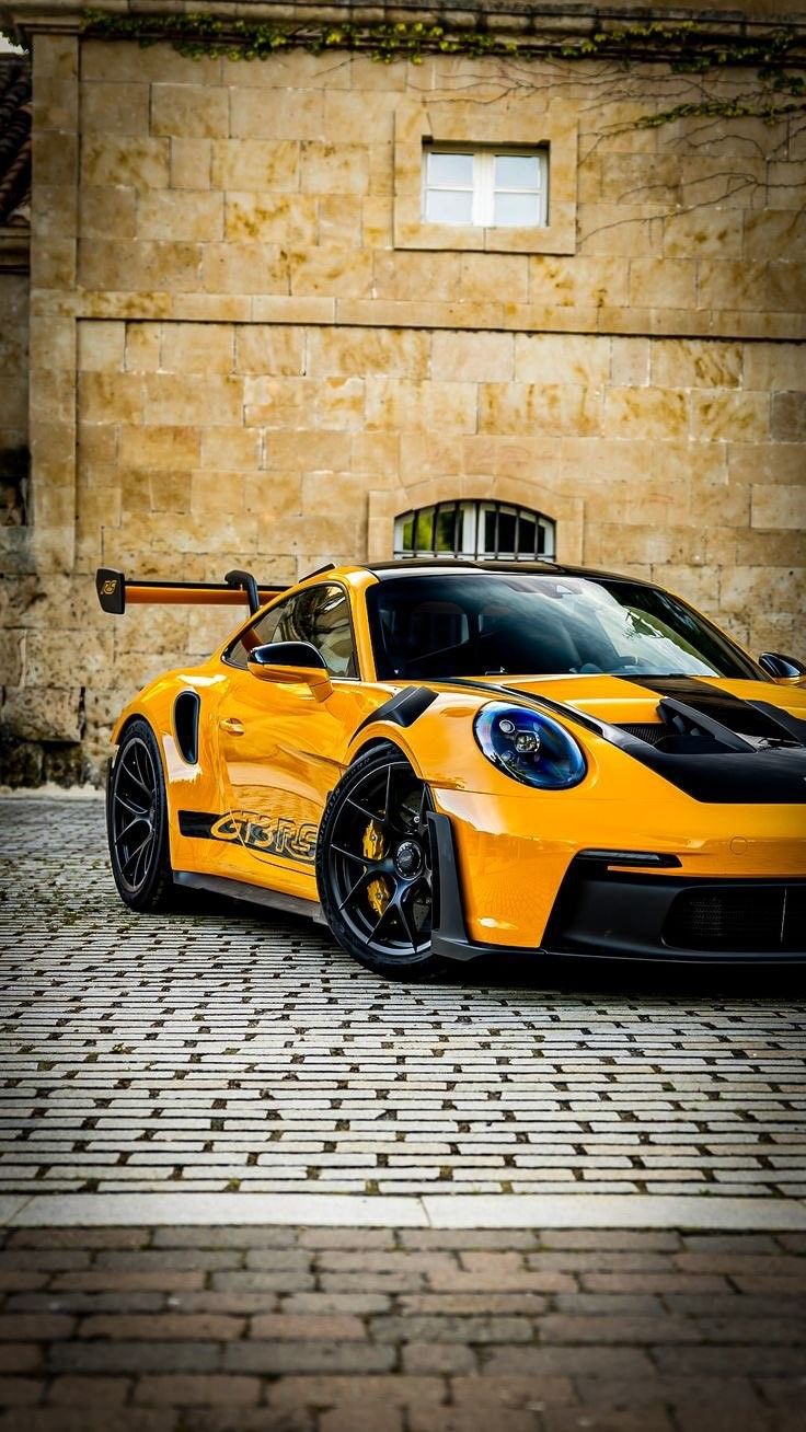 a yellow sports car parked in front of a building