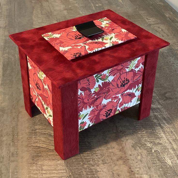 a small red table with flowers painted on it