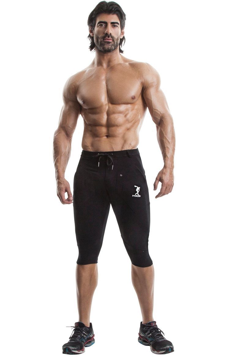 a man in black shorts and no shirt posing for the camera with his hands on his hips