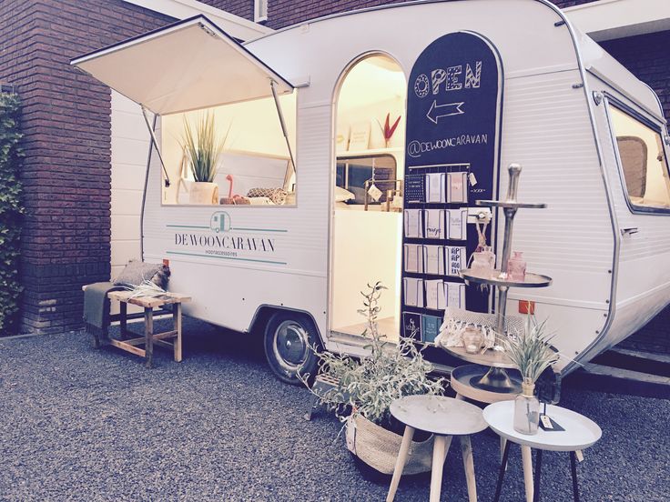 an rv parked in front of a brick building with plants and tables outside the door