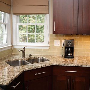 a kitchen with granite counter tops and wooden cabinets, along with a coffee maker on the window sill