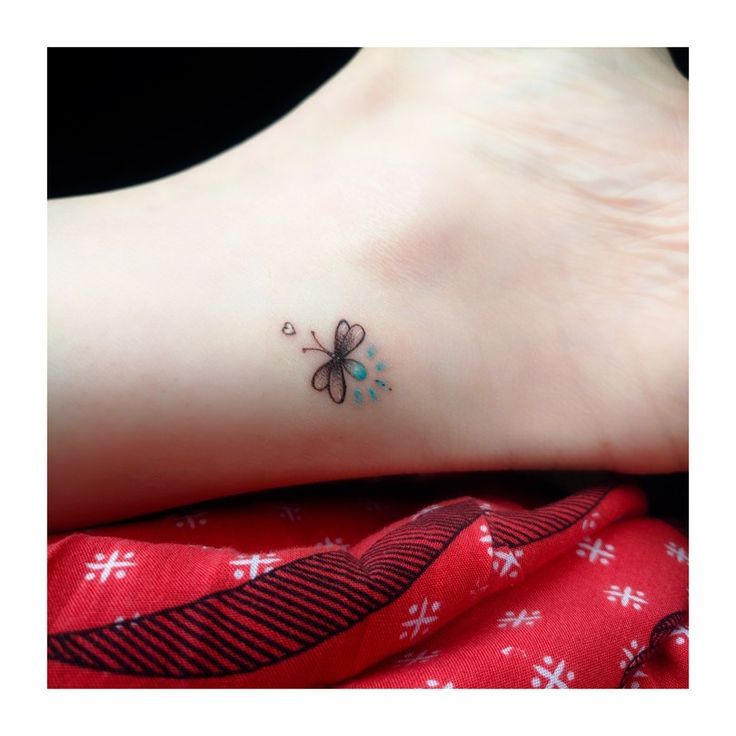 a small tattoo on the foot of a woman's left foot with a butterfly