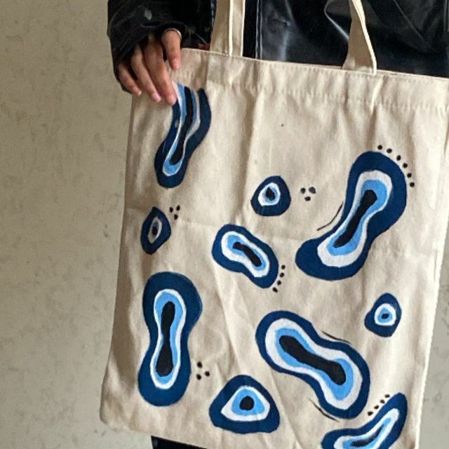 a person holding a tote bag with blue swirls on it