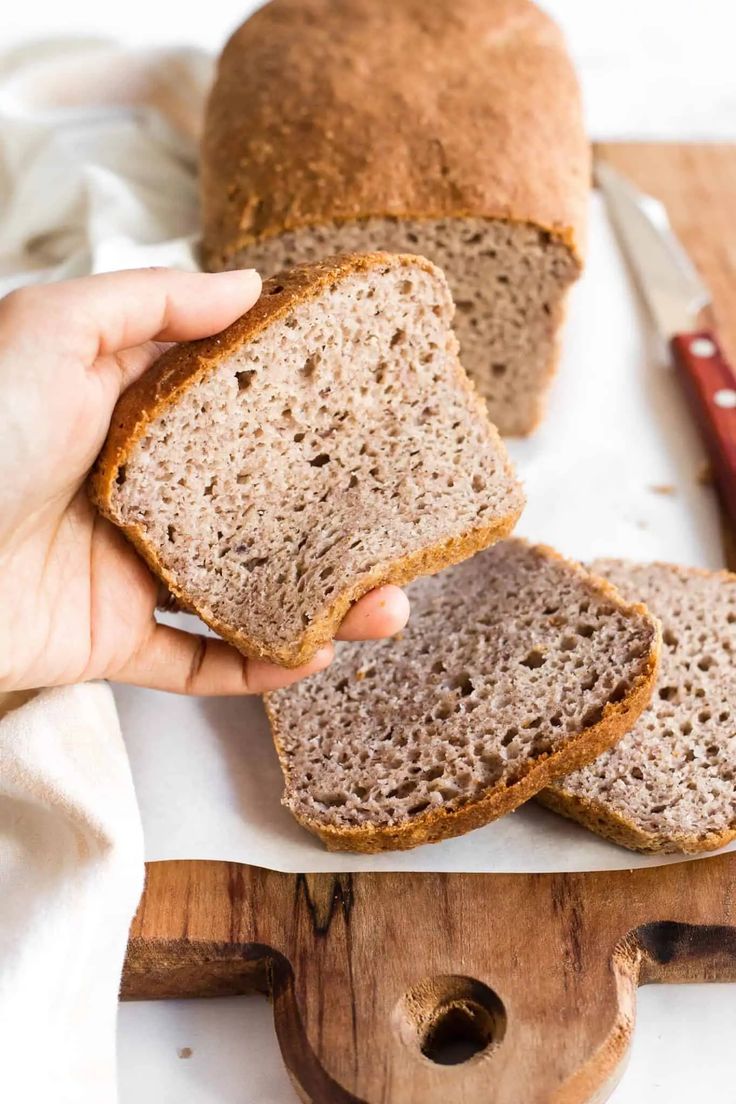 a person holding a loaf of bread on top of a cutting board next to a knife