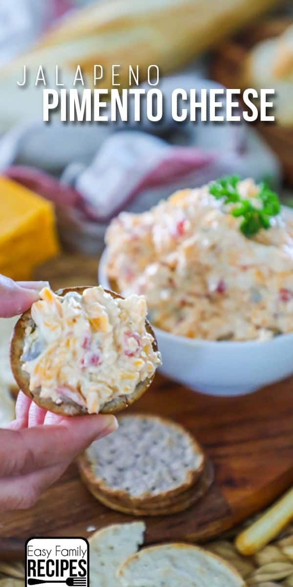 someone is holding up a piece of bread with dip in the middle and crackers on the side