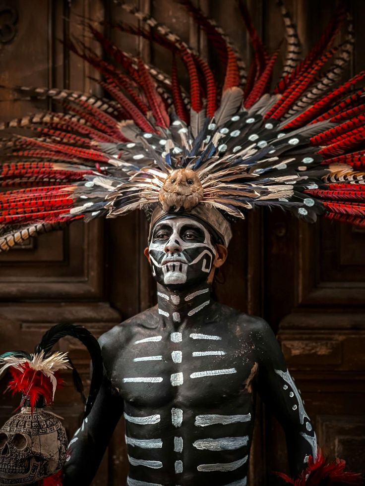 a skeleton with feathers on it's head standing in front of a wooden door