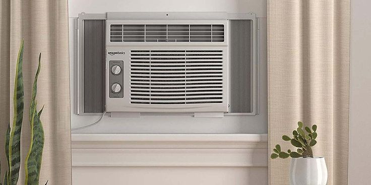 an air conditioner sitting on top of a window sill next to a potted plant