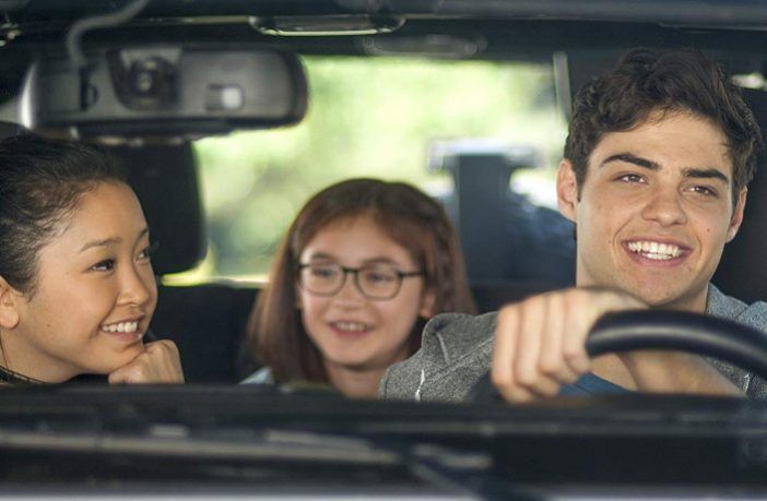 three people sitting in the back seat of a car