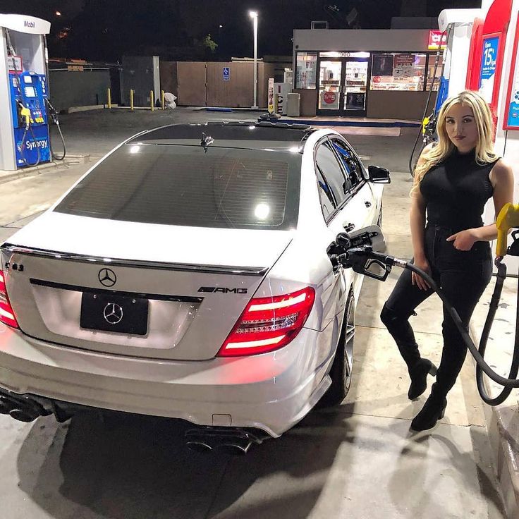 a woman pumping gas into her car at a gas station