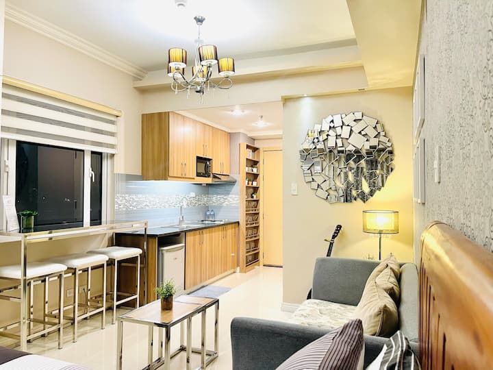 a living room filled with furniture and a flat screen tv mounted to the wall next to a kitchen