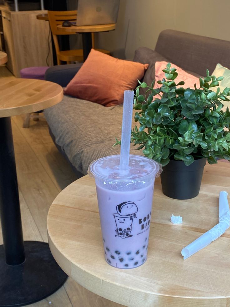 a drink sitting on top of a table next to a potted plant