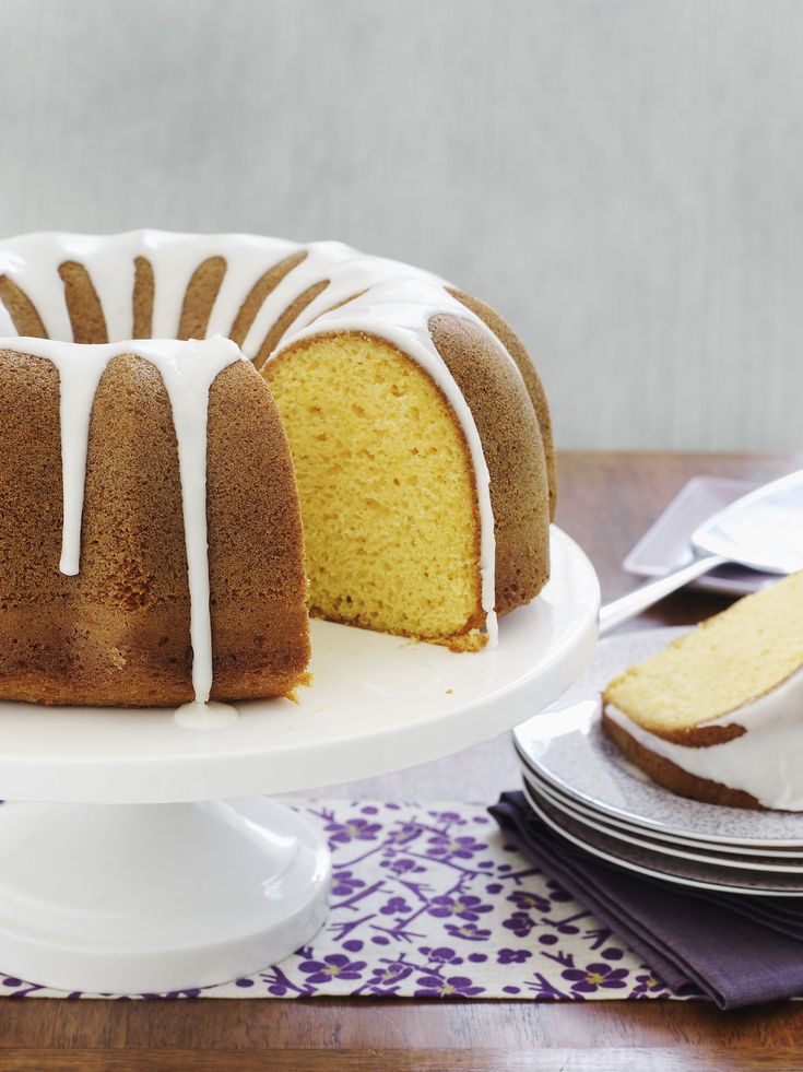 a bundt cake with white icing sitting on top of a table next to plates