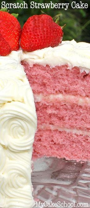 a close up of a slice of strawberry cake with white frosting and two strawberries on top