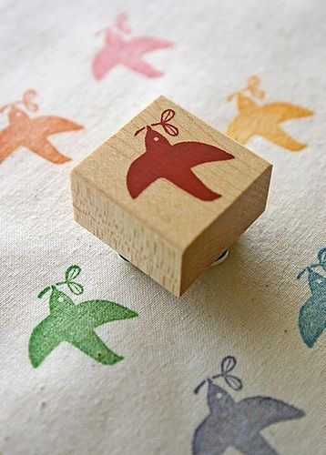 a rubber stamp with birds on it sitting on top of a fabric covered tablecloth