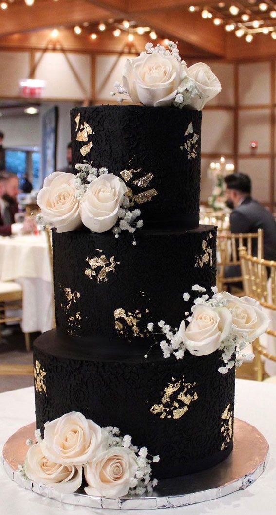 a black and gold wedding cake with white flowers