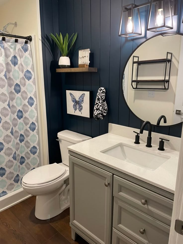 a white toilet sitting next to a bathroom sink under a mirror in a room with blue walls