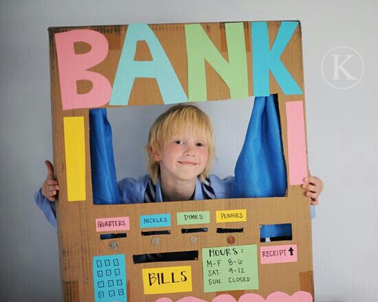 a child holding up a cardboard bank machine