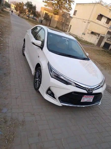 a white car parked on the side of a road next to a brick walkway and trees