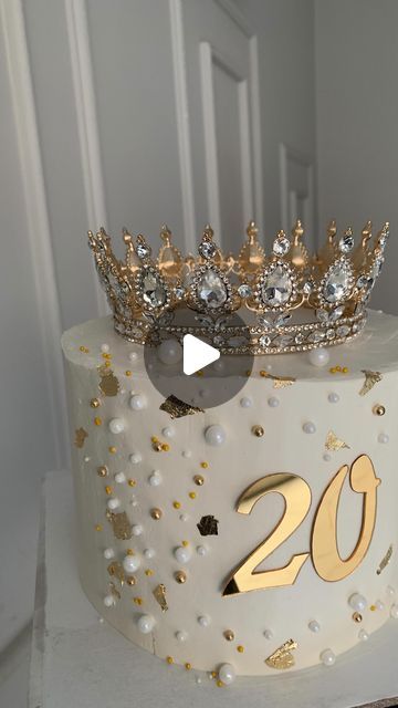 a white cake with gold decorations and a crown on top that says 20th birthday,