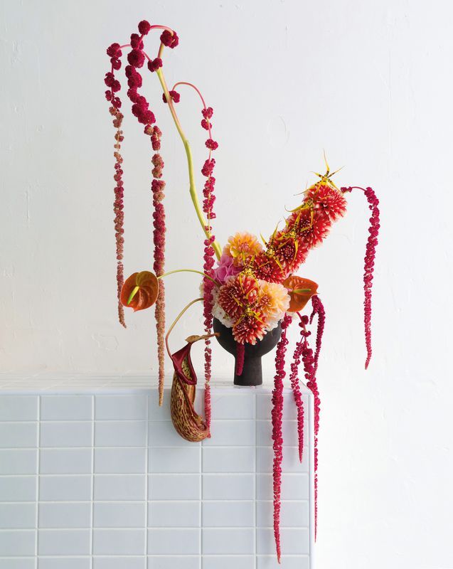 a vase filled with flowers sitting on top of a white tiled counter next to a wall