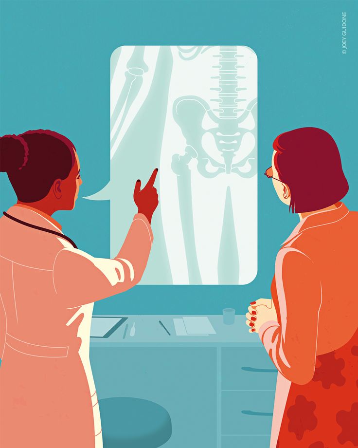 two women standing in front of a tv with a skeleton on the wall behind them