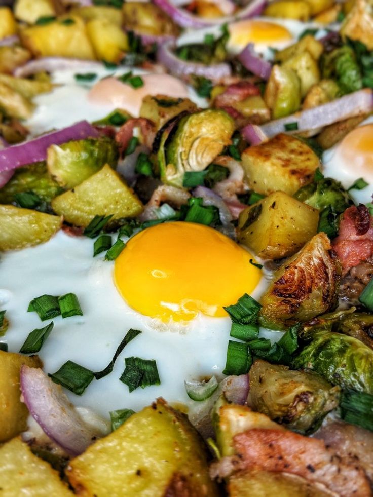 an egg is sitting on top of some potatoes and other veggies in a pan