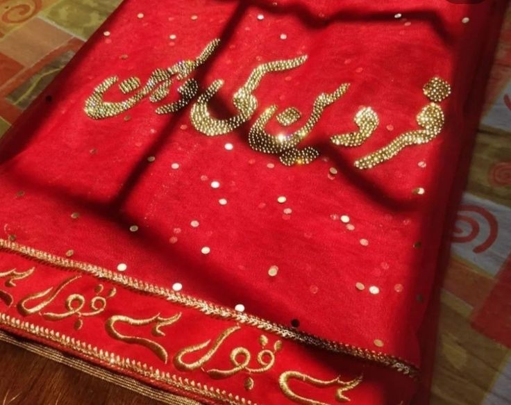 a red and gold cloth with the word eid written in arabic letters on it