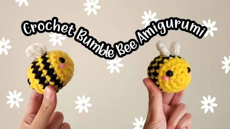 two crocheted bumbees are being held up to the camera with their fingers