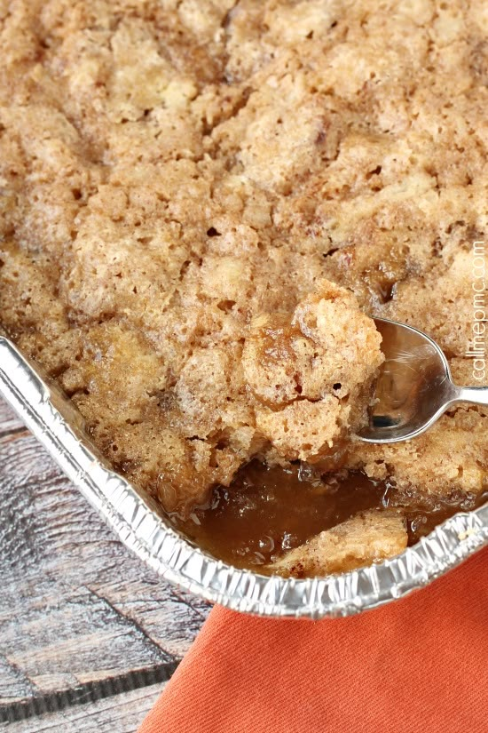 a close up of a pie in a pan on a wooden table with a spoon