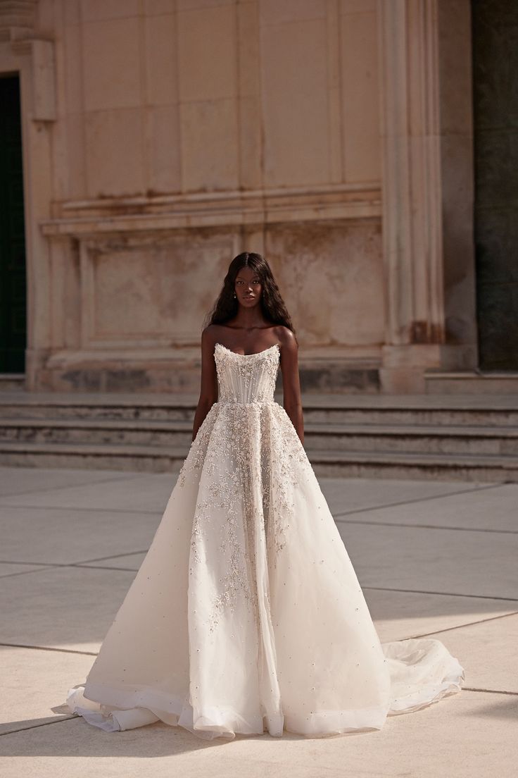 a woman in a white wedding dress standing on the ground with her back to the camera