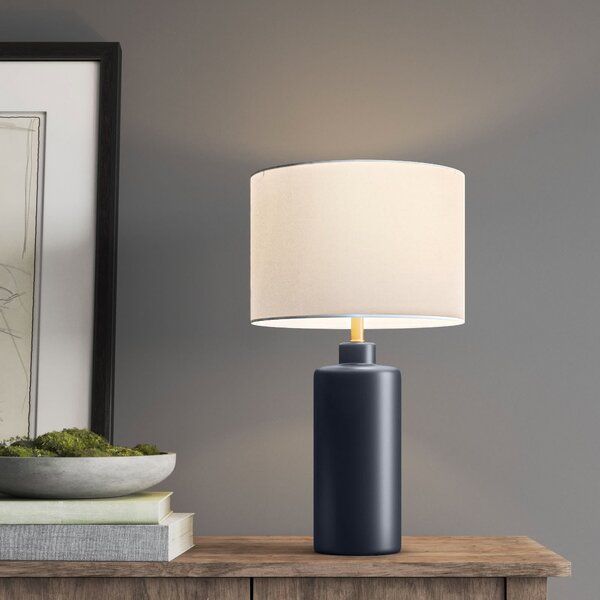 a table lamp sitting on top of a wooden dresser next to a bowl of moss