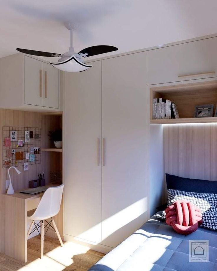 a bedroom with a bed, desk and ceiling fan in the corner next to it